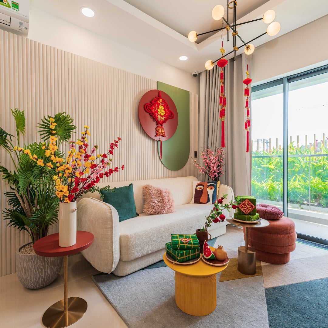 Modern living room with a beige sofa, colorful decor, and large windows.