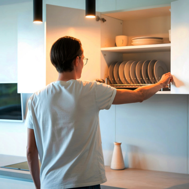 Person reaching into a kitchen cabinet to take out a plate.