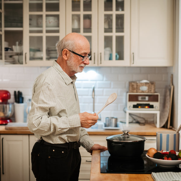 Man cooking in a kitchen holding a wooden spoon