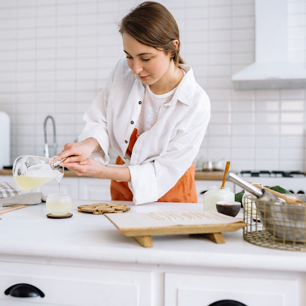Woman pouring a liquid into a glass in a kitchen.